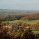 Longleat house surrounded by green fields and orange trees. The viewpoint is from a hill above the house