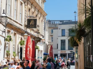 The Garrick's Head pub facade. People sit in the street on chairs in attendance to the pub. The day is bright and summery.