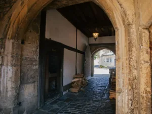 A medieval archway, with old exposed brick, logs and barrels. This is the entrance to a pub in Norton St Philip