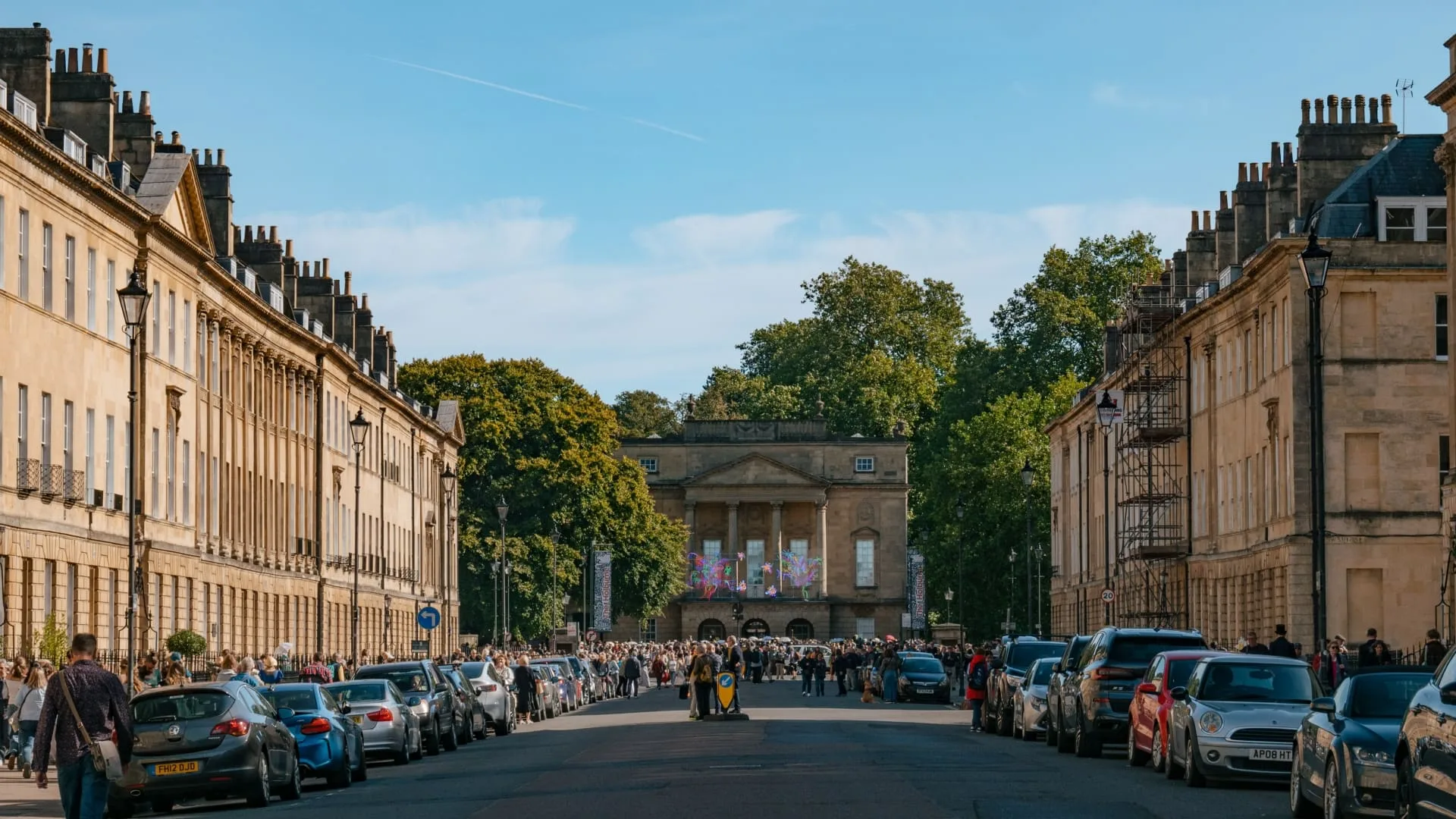 A view down the street of the Holburne Museum in Bath, a grand Georgian building with a distinctive arched entrance.