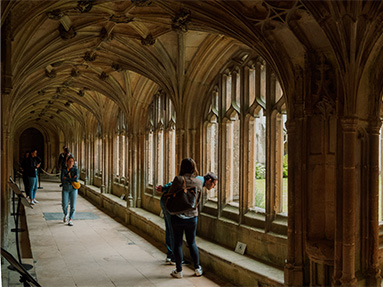 Lacock Abbey cloisters with people walking among the corridor.
